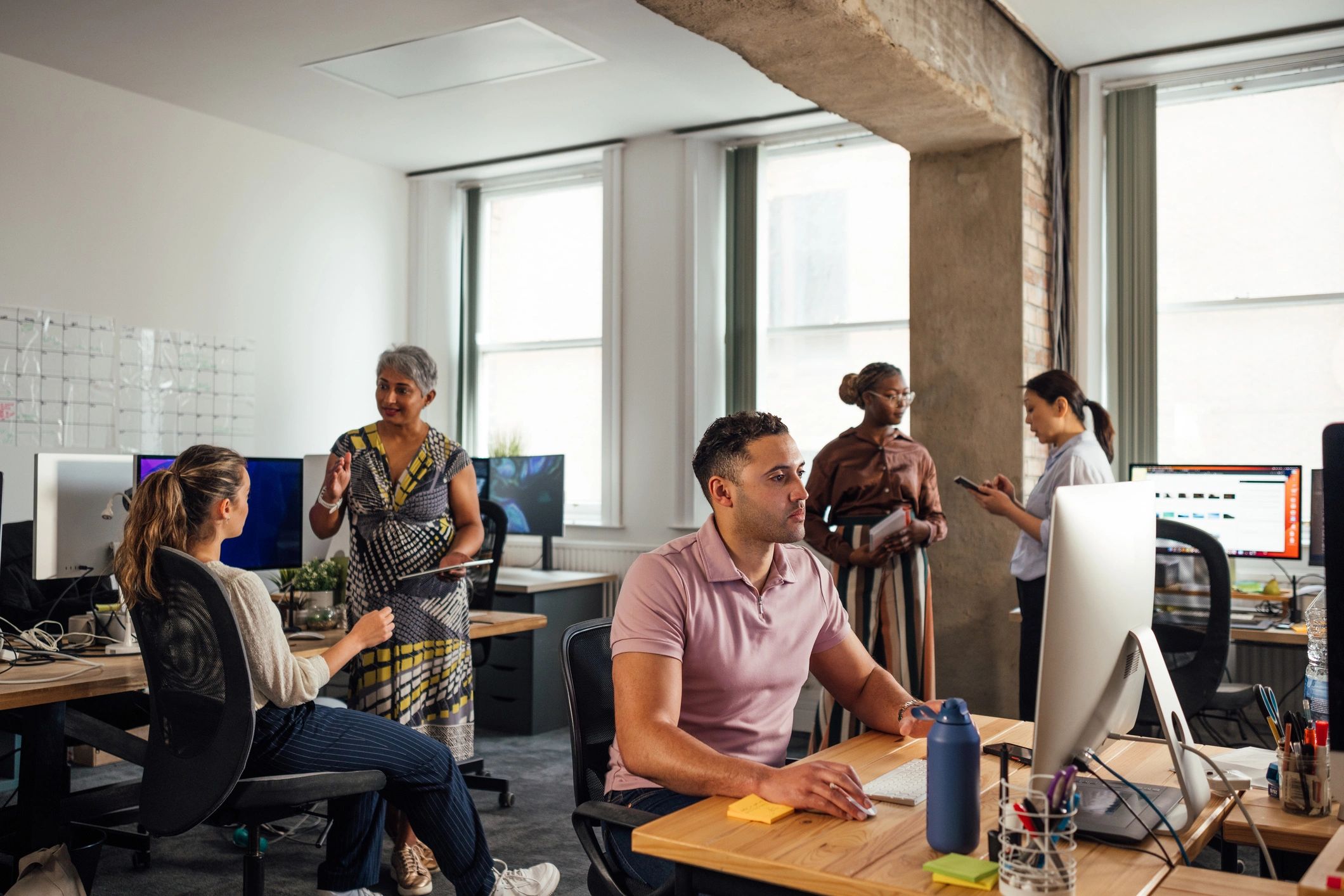 Modern editorial workspace with team members collaborating